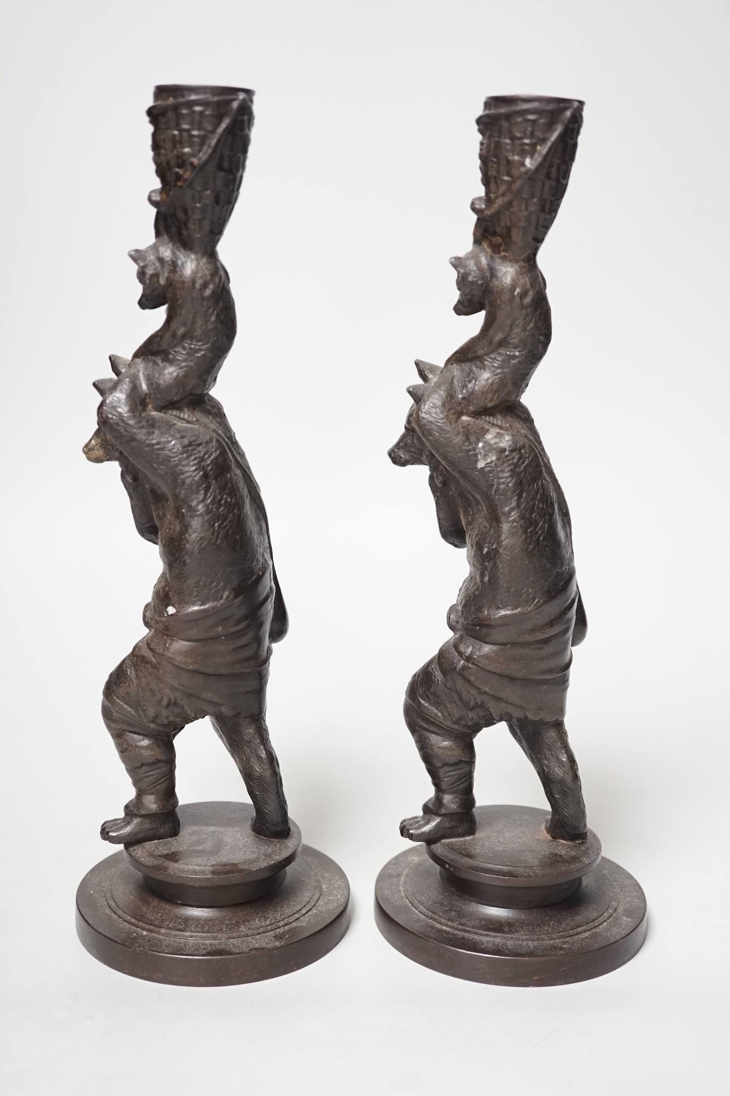 A pair of cast iron candlesticks in the form of anthropomorphised foxes and cubs. 27cm tall